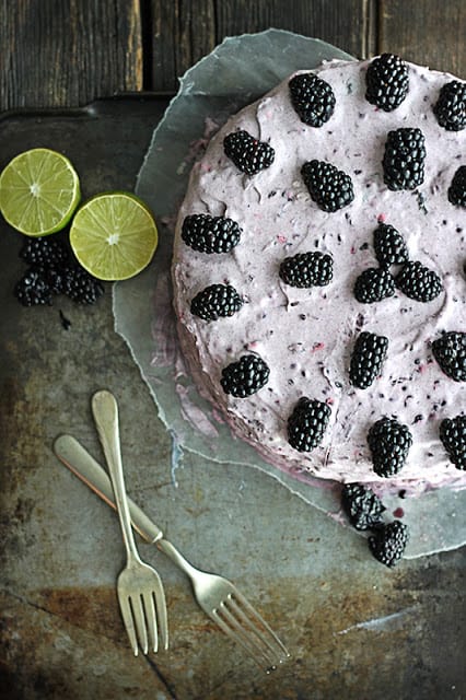 blackberry lime cake on baking sheet with limes, blackberries and criss crossed forks.