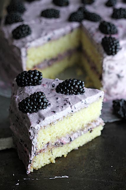 blackberry lime cake with a slice of cake in front of it.