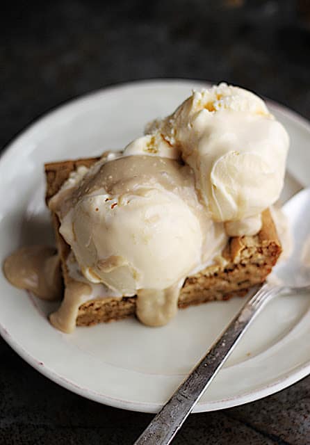 blondie sundaes with hot maple cream sauce on white plate with spoon.