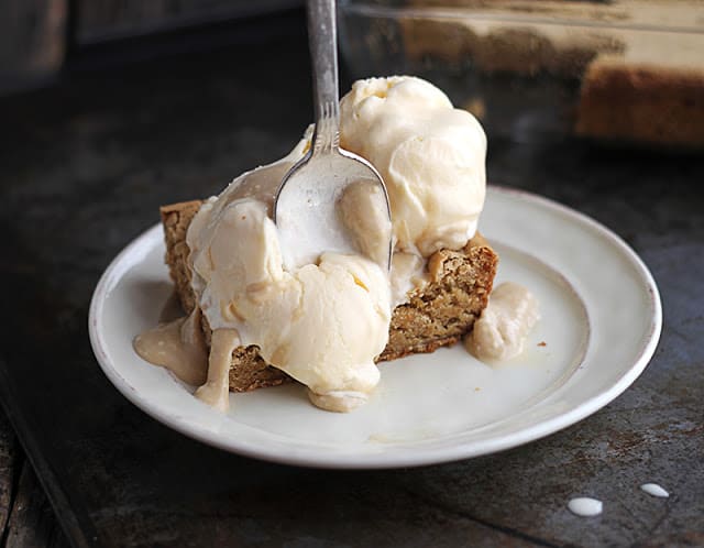 blondie sundaes with hot maple cream sauce on white plate with a spoon.
