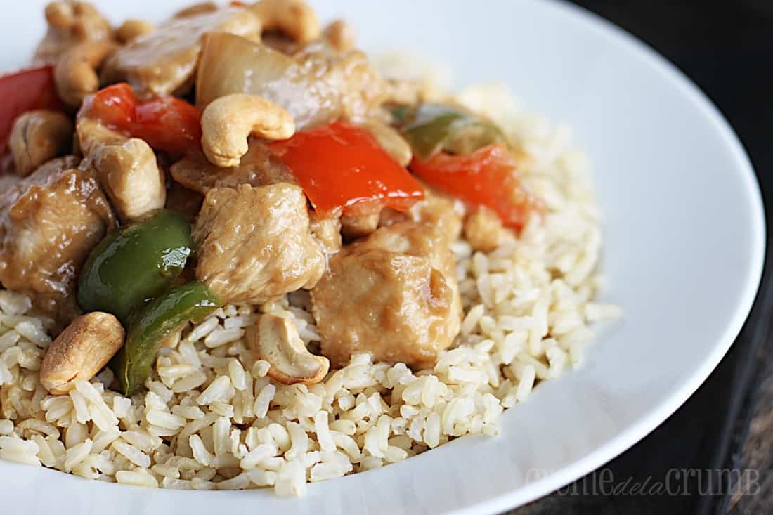 cashew chicken on rice in a white bowl.