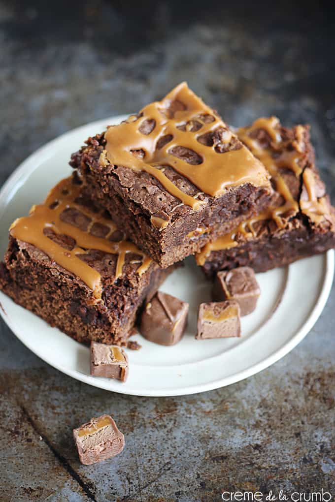 three stacked brownies on a plate with pieces of milky way candy.