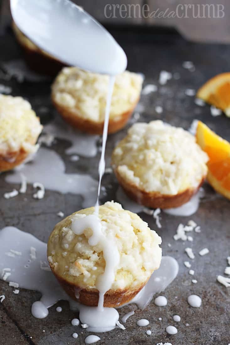 muffins on a baking sheet being drizzled with coconut streusel. 