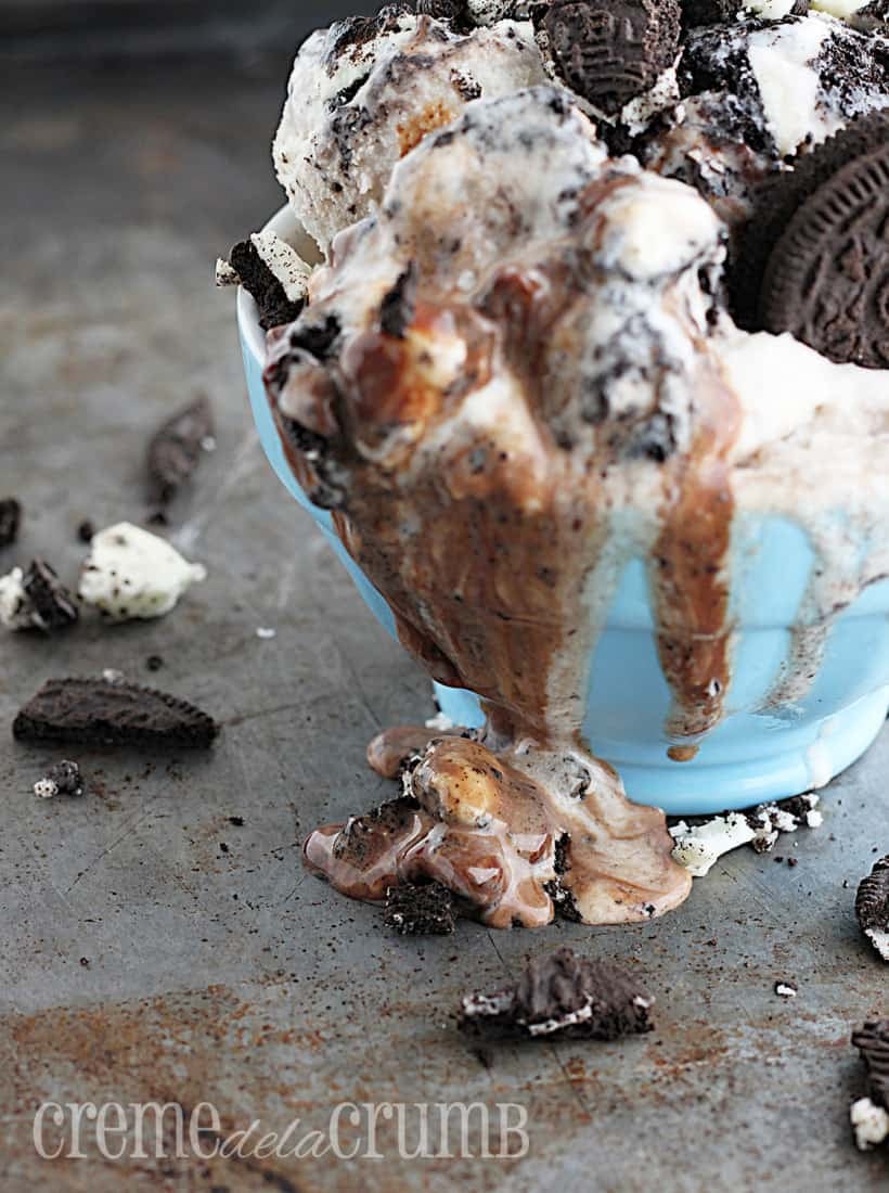 side view of ice cream in blue bowl on a baking sheet with crushed Oreos.