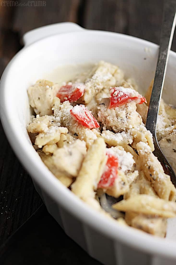  baked penne pasta in an oval shaped serving bowl with serving spoon.