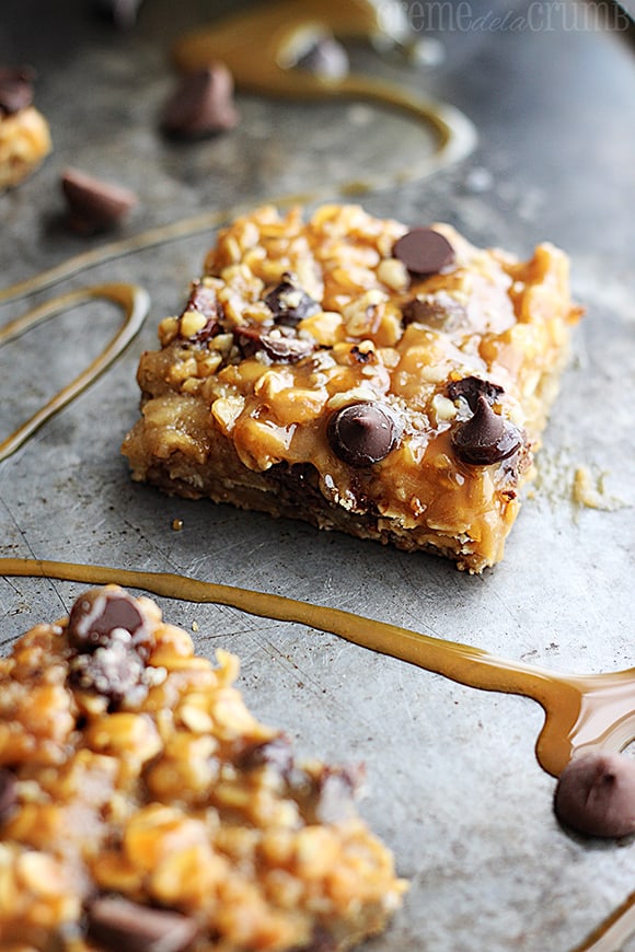 caramel chocolate chip oat bar on a baking sheet with caramel and chocolate chips.