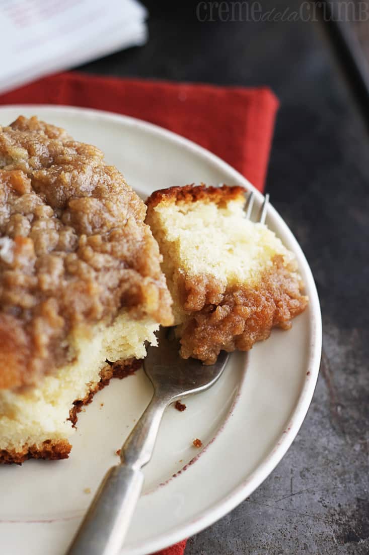 a piece of crumb cake with a bite on a fork on a plate.