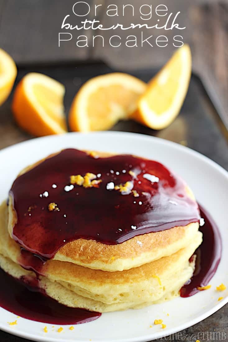 stacked pancakes with fruit syrup on a plate on a baking sheet with slices of an orange faded in the background with the title written on the top of the image.