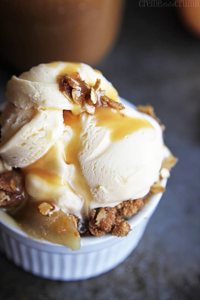 apple crisp with salted caramel sauce and ice cream in a small white bowl.