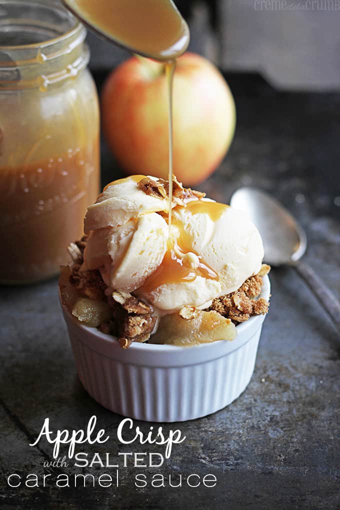 salted caramel sauce being poured on top of a bowl of apple crisp and ice cream with a mason jar of sauce, an apple, and a spoon in the background with the title of the recipe written on the bottom left corner of the image.