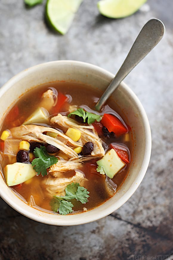 top view of baja chicken soup in bowl with spoon and slices of a lime faded in the background.