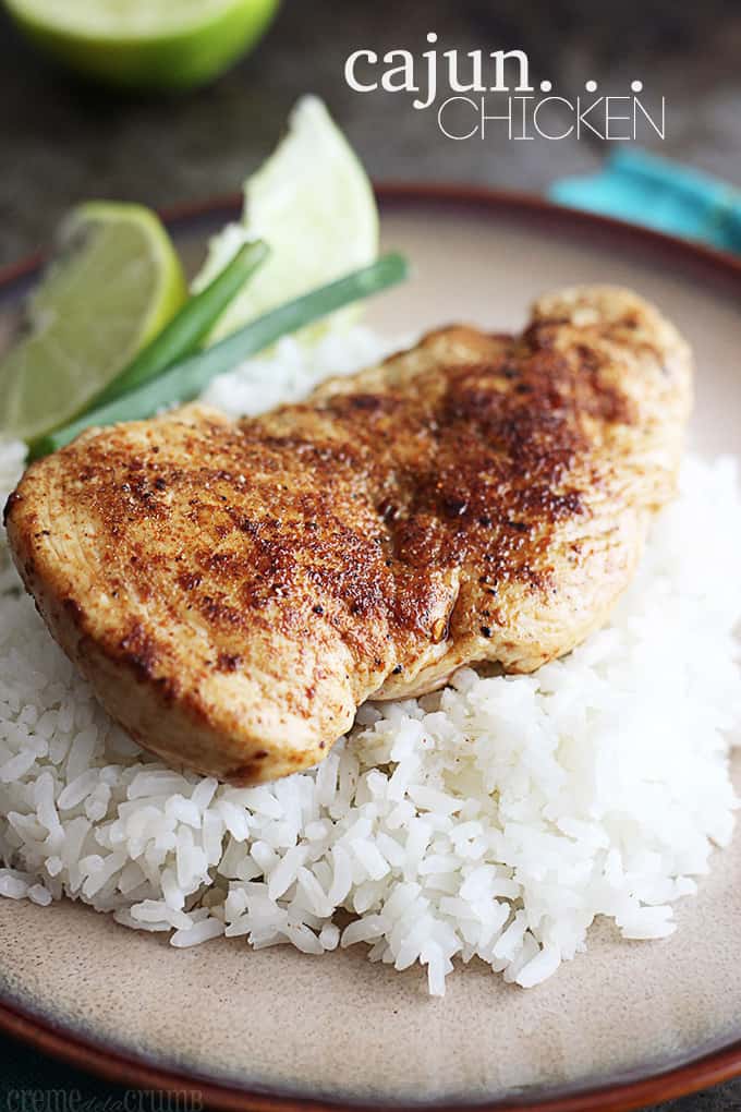 cajun chicken on rice with green onion and a slice of lemon on a plate with the title written on the top right of the image.