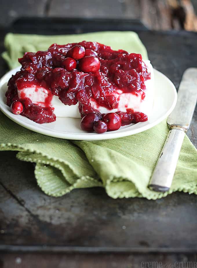 chipotle cranberry cream cheese dip on a plate on a green cloth napkin with a knife.