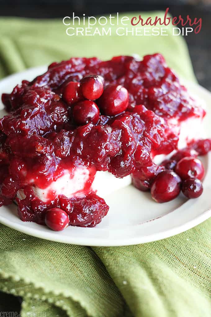 chipotle cranberry cream cheese dip on a plate on top of a green cloth napkin with the title of the recipe written on the top right corner of the image.