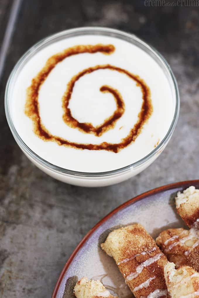 glaze dip in a bowl with cinnamon roll dippers on a plate on the side.