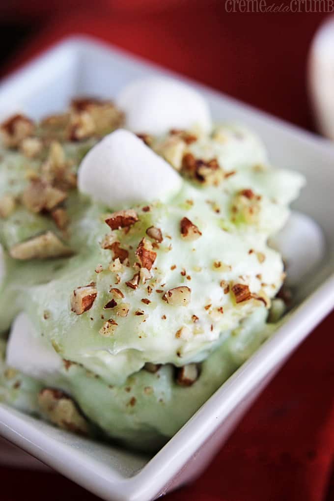 up close view of pistachio pudding jello salad in a small white square bowl.