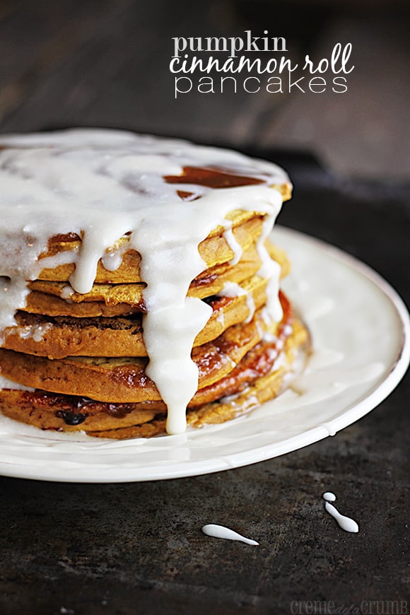 stacked pumpkin cinnamon roll pancakes on a plate with the title of the recipe written on the top right corner of the image.