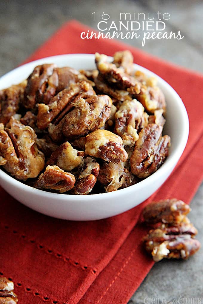 candied cinnamon pecans in a bowl on top of a red cloth napkin with the title of the recipe written on the top right corner of the image.