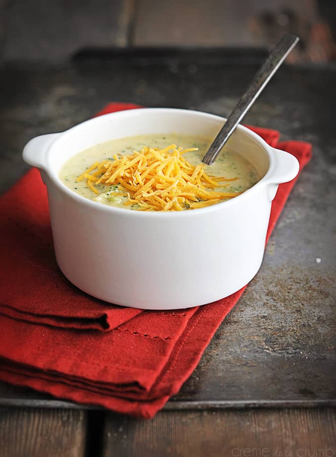 {copycat} Panera Bread cheddar broccoli soup and a spoon in a bowl on top of a red cloth napkin.