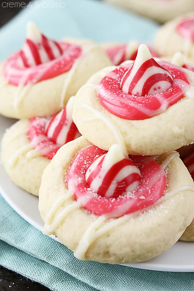 close up of peppermint Kiss thumbprint cookies on a plate on a cloth napkin.