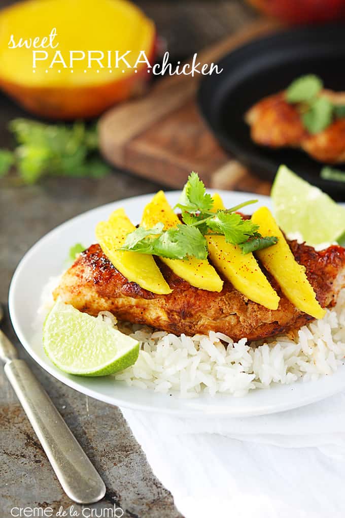sweet paprika chicken on rice topped with mango slices and cilantro leaves with slices of a lime on the side of the plate with the title of the recipe written on the top left corner of the image.