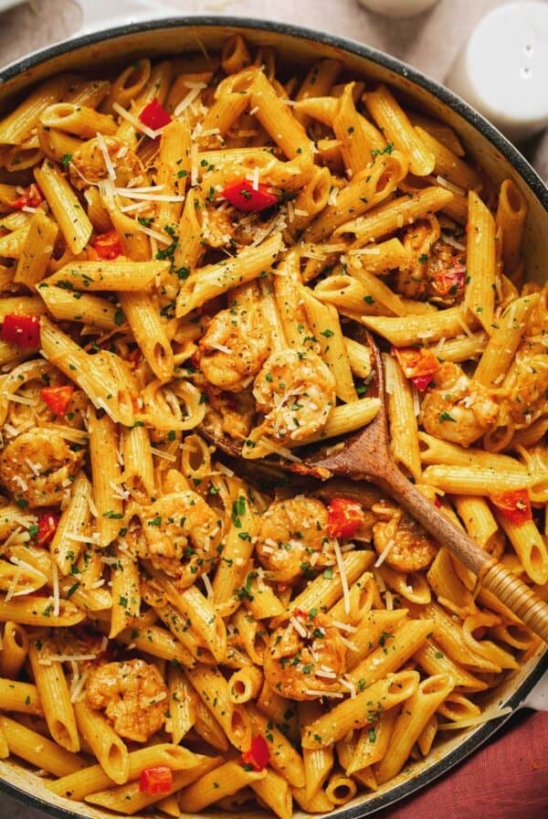 Overhead of creamy Cajun shrimp pasta with a wooden serving spoon in a skillet.