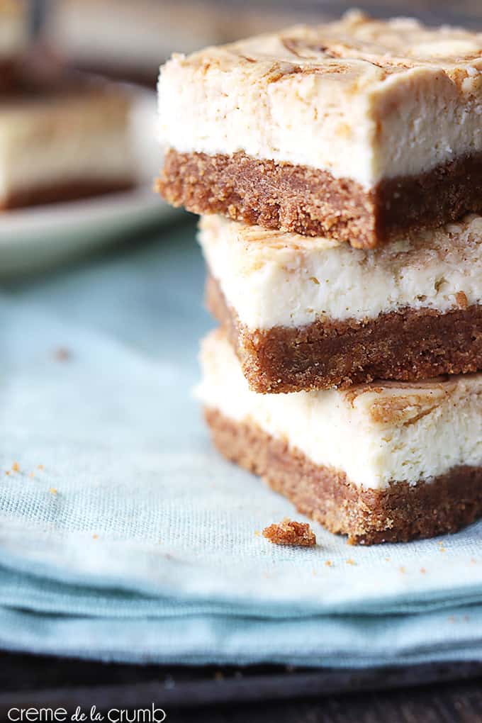 stacked cinnamon roll cheesecake bars on a blue cloth napkin.