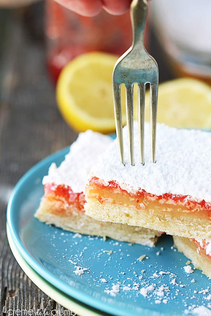 raspberry lemon bars on a plate with a fork in the top bar.