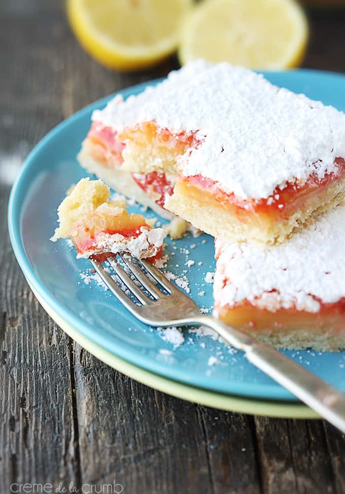 raspberry lemon bars and a fork with a bite from one of the bars on it on a plate.