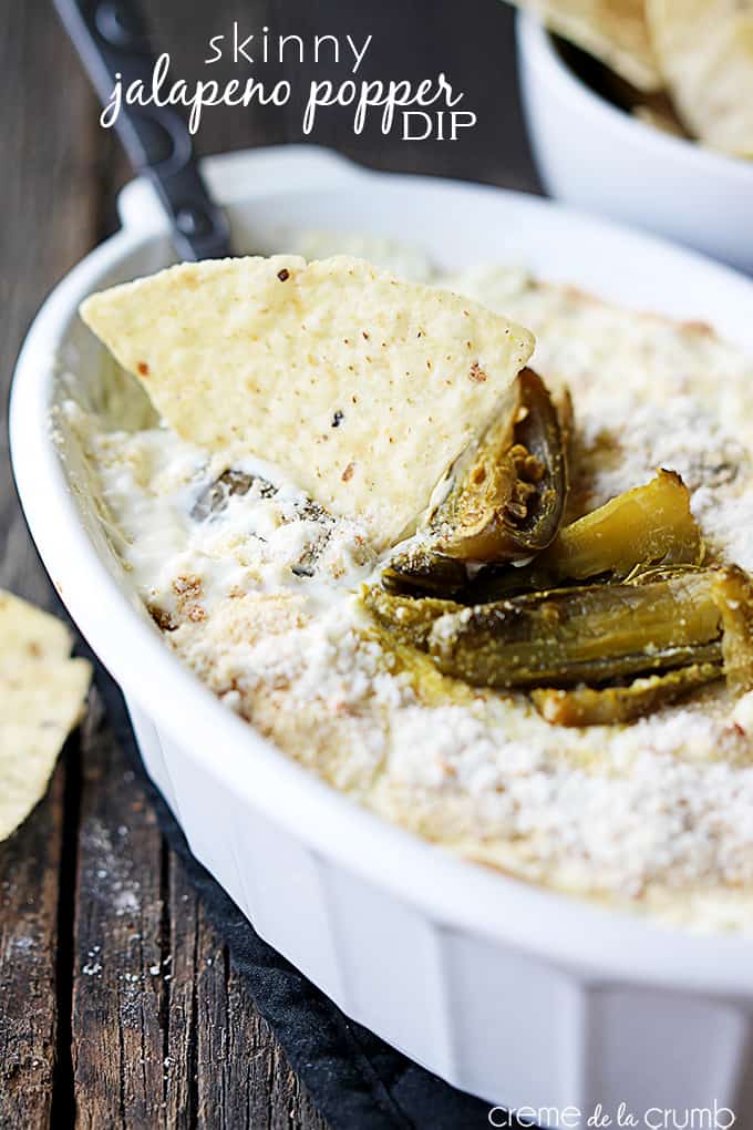 skinny Jalapeño popper dip with a serving spoon and chip dipped in it in a serving bowl.