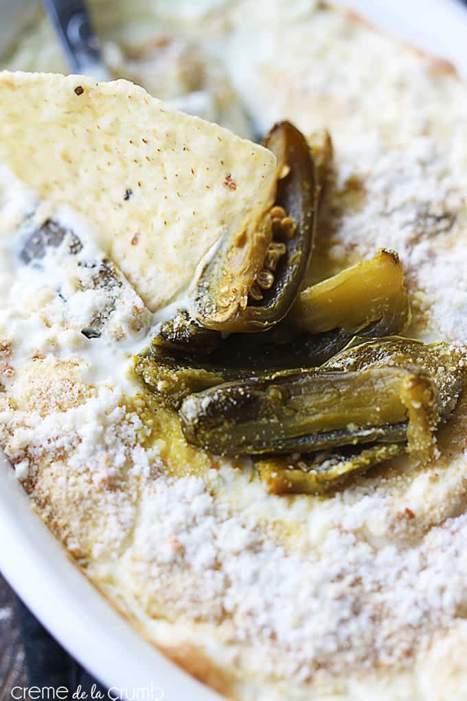 close up of skinny Jalapeño popper dip with a serving spoon and a chip dipped in it in a serving bowl.