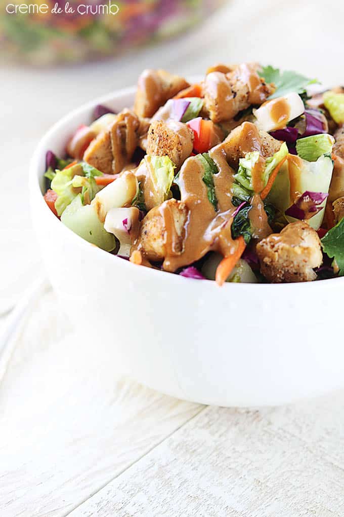 Thai chicken chopped salad in a bowl with dressing on top.