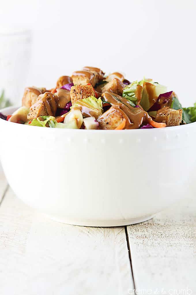 side view of Thai chicken chopped salad in a bowl with dressing on top.