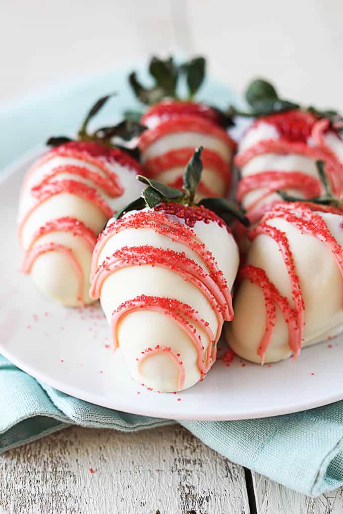 white chocolate dipped strawberries on a plate on a blue cloth napkin.