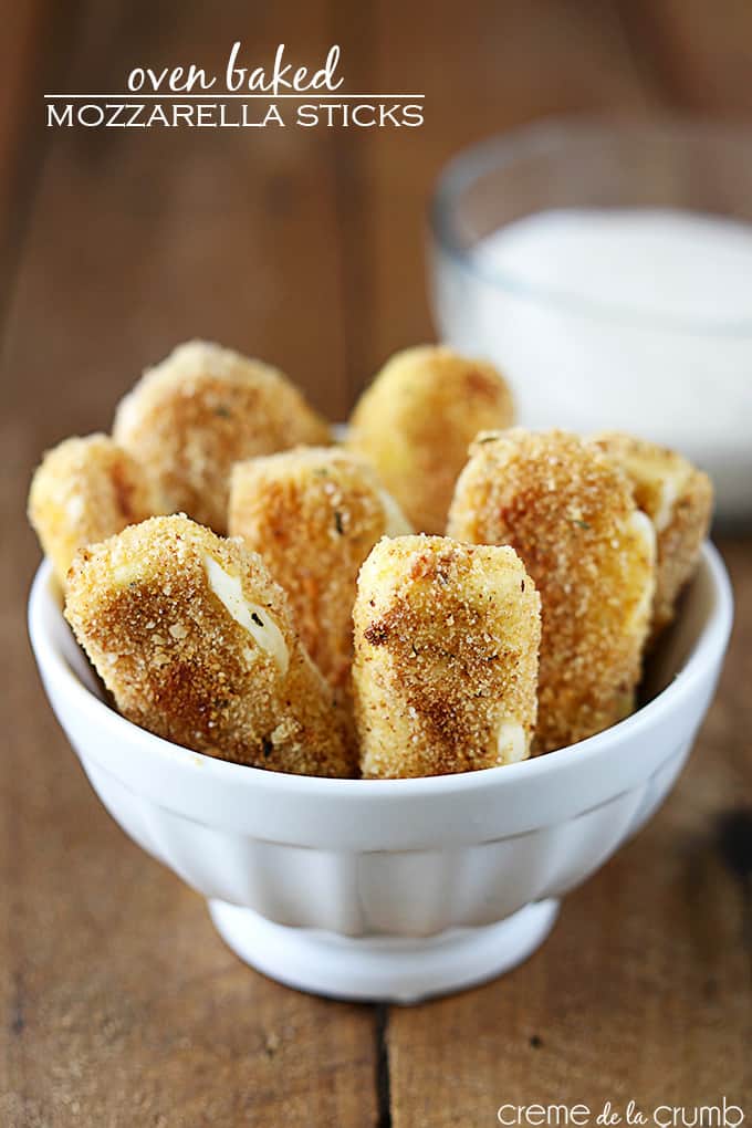 oven baked mozzarella sticks in a bowl with ranch in a bowl faded in the background with the title of the recipe written on the top left corner of the image.