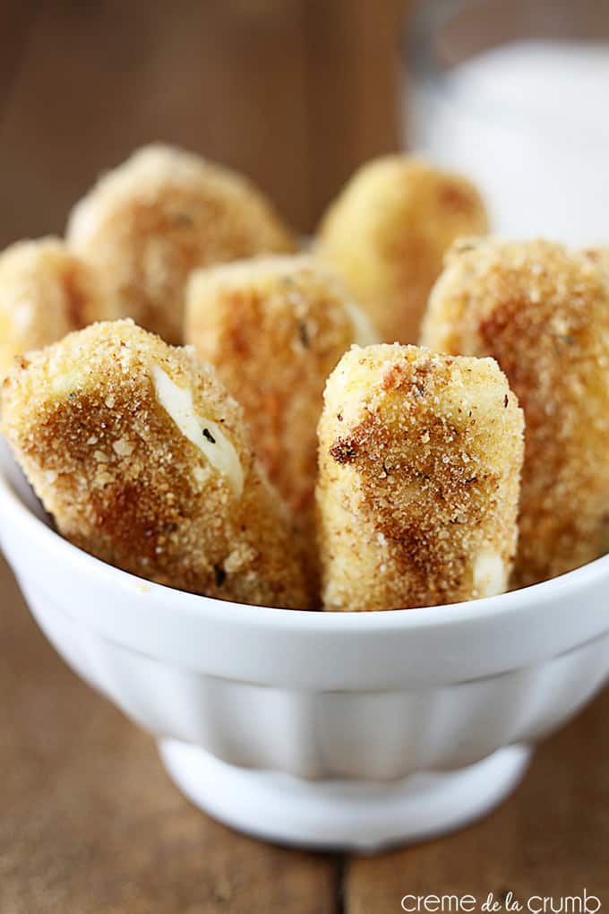 close up of oven baked mozzarella sticks in a bowl.