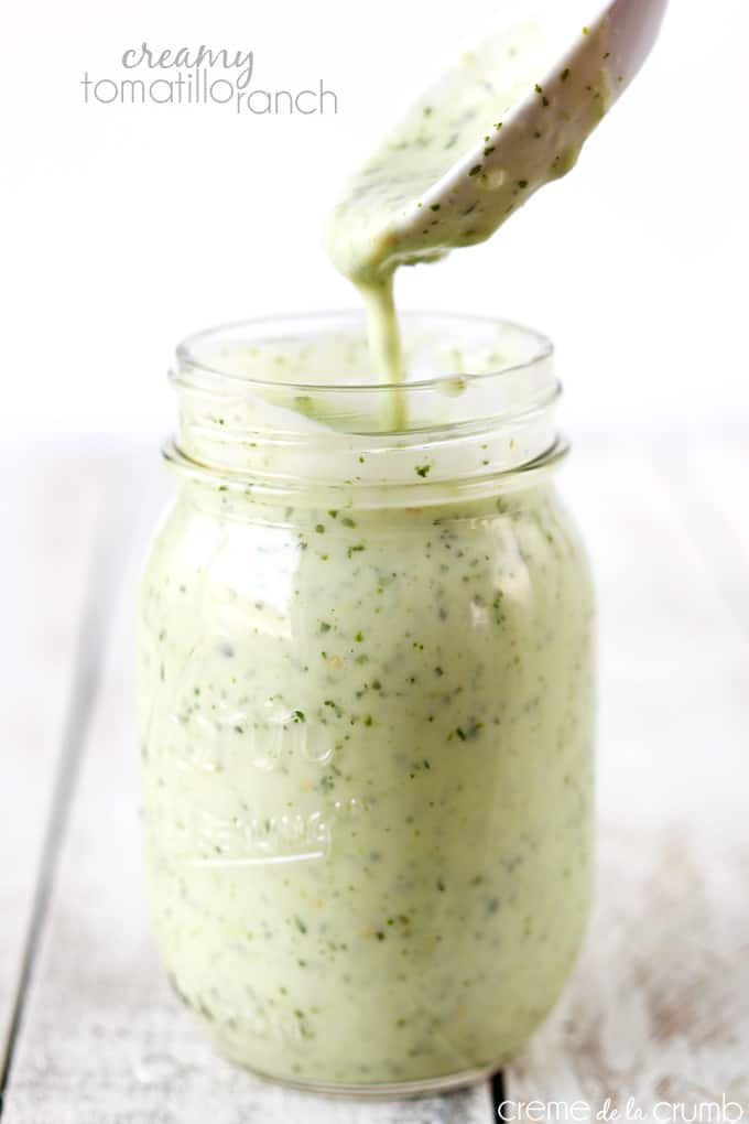 Cafe Rio copycat creamy tomatillo ranch in a mason jar with a spoon pouring some inside the jar with the title of the recipe written on the top left corner of the image.