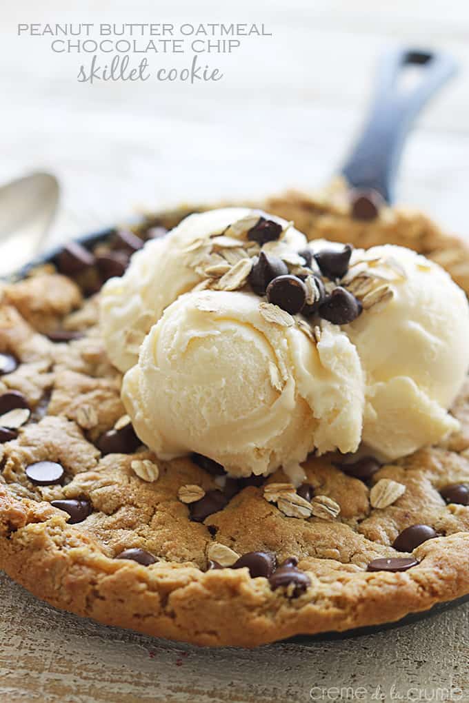 peanut butter oatmeal chocolate chip skillet cookie in a skillet topped with vanilla ice cream, chocolate chips, and oats with the title of the recipe written on the top left corner of the image.
