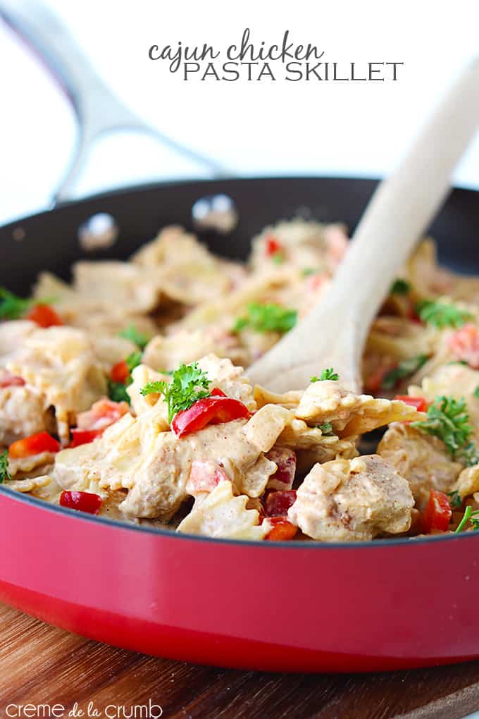 Cajun chicken pasta skillet with a spatula in a skillet with the title of the recipe written on the top middle of the image.