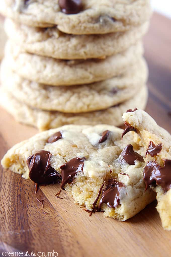 two halves of a double chewy chocolate chip cookie on top of one another with more cookies stacked in the background.