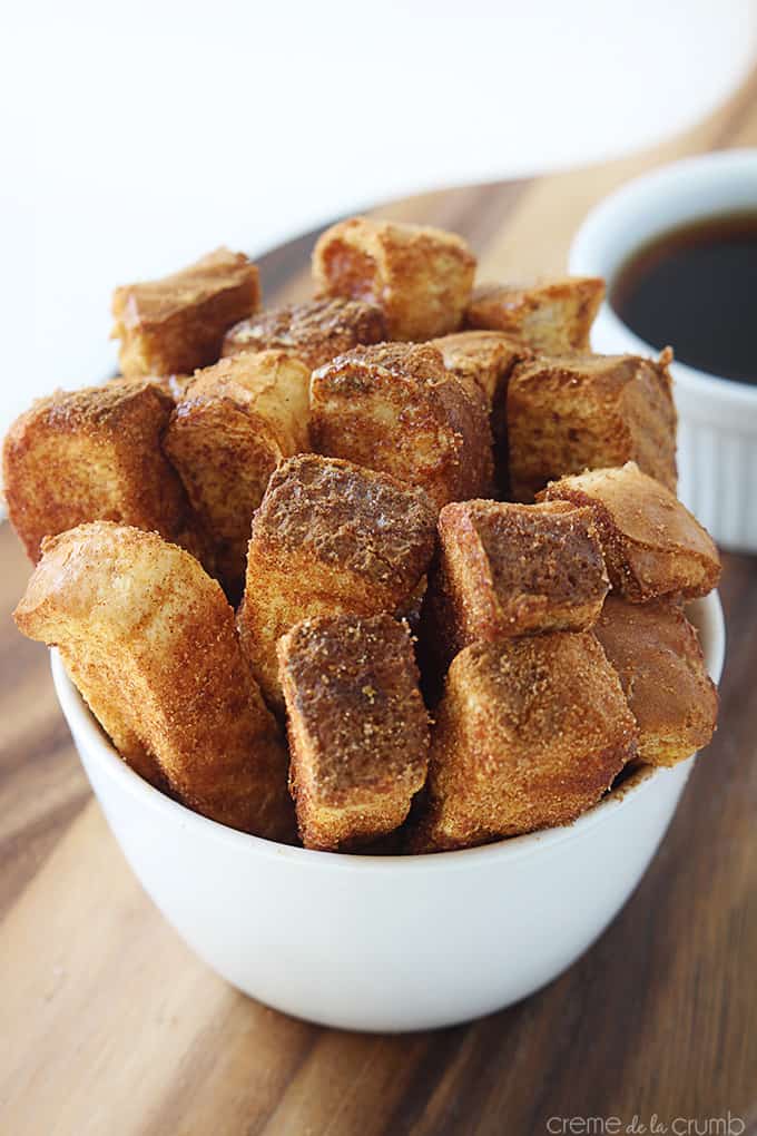 cinnamon French toast sticks in a bowl with syrup in a dipping bowl faded in the background.