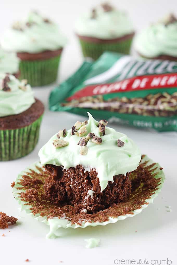 a Andes mint grasshopper cupcake with a bite taken out of it with more cupcakes and an Andes mint bag faded in the background.
