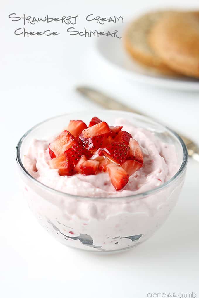 strawberry cream cheese shmear with chopped strawberries on the top with a knife and a bagel on a plate faded in the background with the title of the recipe written on the top left corner of the image.