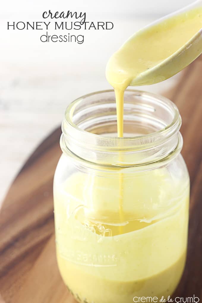 creamy honey mustard dressing in a mason jar with a spoon pouring some dressing into the jar with the title of the recipe written on the top left corner of the image.