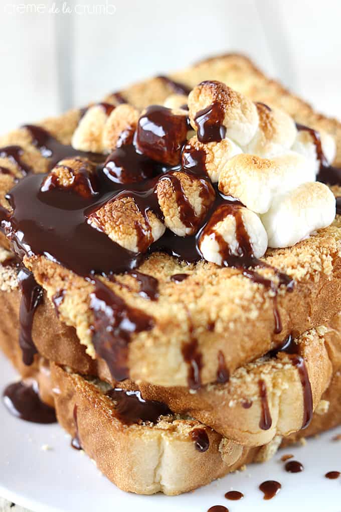 close up of S'mores French toast on a plate topped with marshmallows and chocolate syrup.