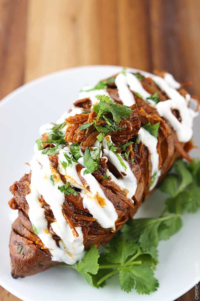 top view of a bbq pulled pork stuffed hasselback sweet potato on a plate.
