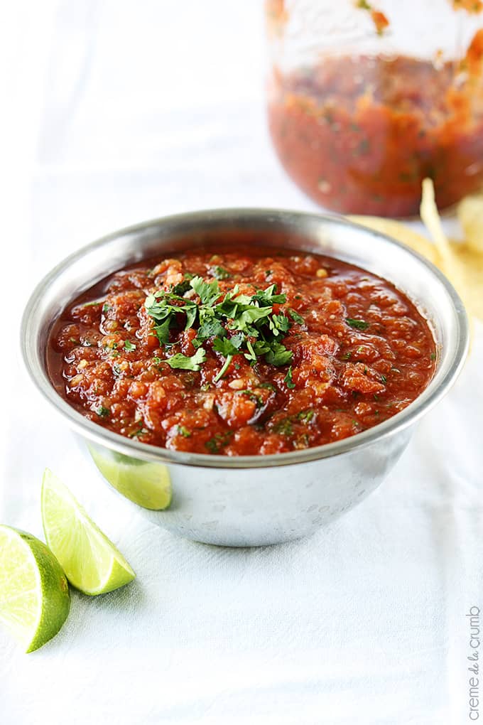 blender salsa in a bowl with slices of limes on the side.