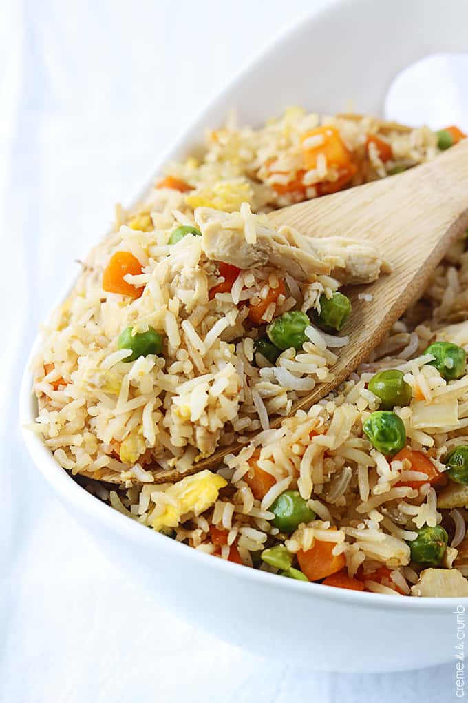 chicken fried rice with a wooden spoon in a serving tray.