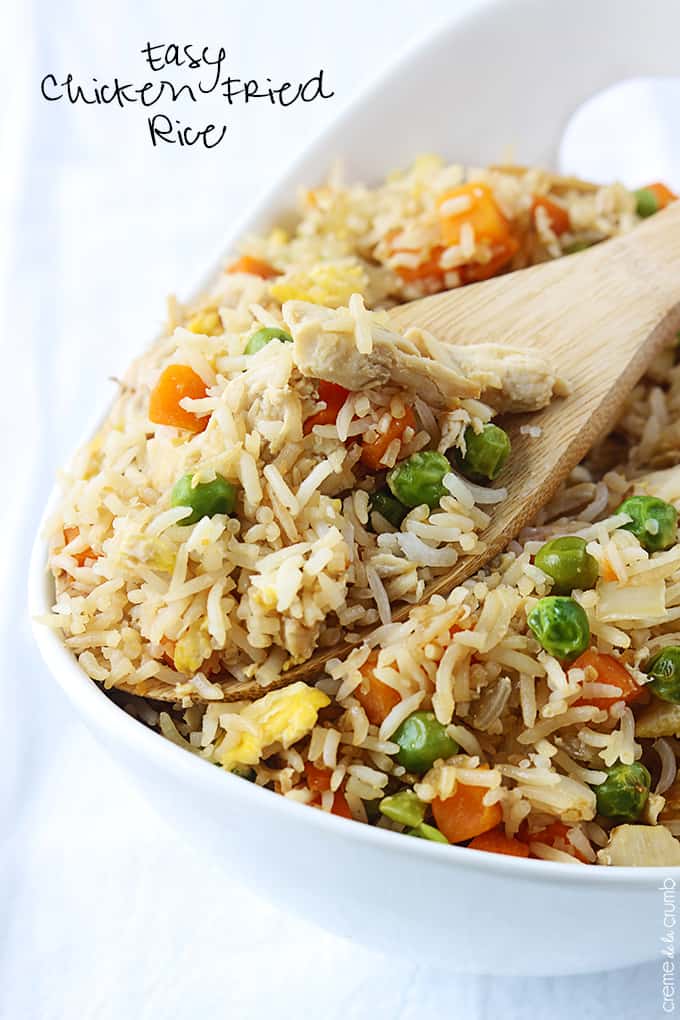 chicken fried rice in a serving tray with a wooden spoon with the title of the recipe written on the top left corner of the image.