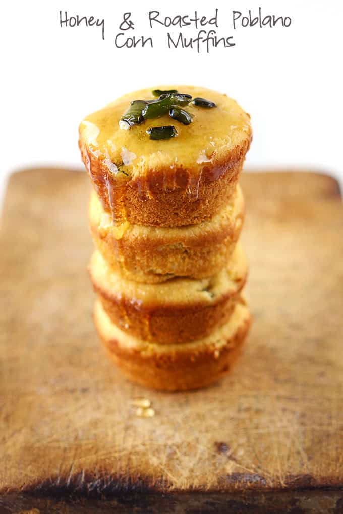 stacked honey poblano corn muffins on a wooden cutting board drizzled with honey with the title of the recipe written on the top of the image.